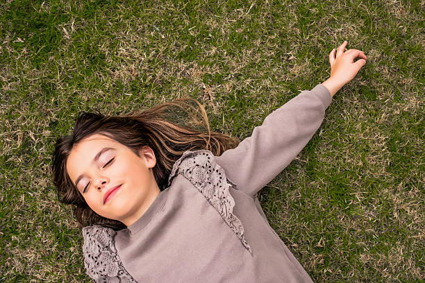 istock Young girl lying on grass with eyes closed, enjoying nature 2209985806