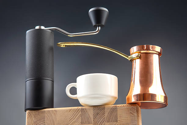 istock A modern manual coffee grinder, copper Turkish cezve, and white ceramic cup on a wooden surface, captured against a dark blue background for a cozy coffee vibe. ( 2209987847