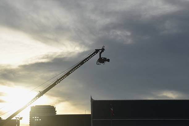 video camera hanging on heavy crane for shooting top view in sunset sky background