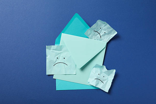 istock Paper envelopes with sad emoji on blue background, top view 2209993176