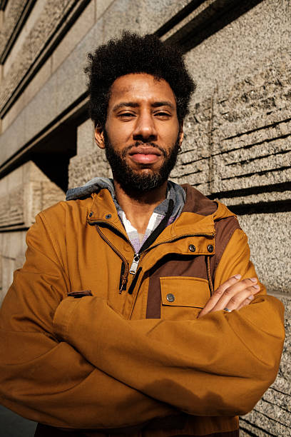 istock Confident black man with folded arms leaning against stone wall 2209994173
