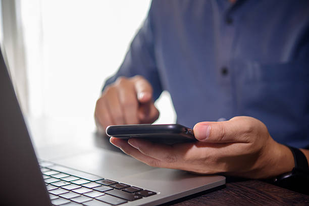 istock Businessman working on laptop and holding smartphone. Modern workspace for office work and communication. 2210017719