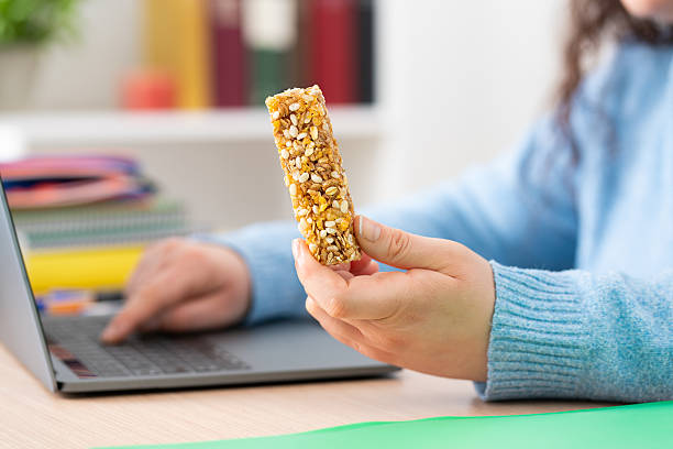 istock Student girl hand holding snack bar using laptop 2210018239