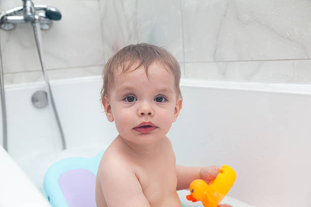 istock Baby taking a bath. Baby washing in a bathtub with ducks. 2210020157