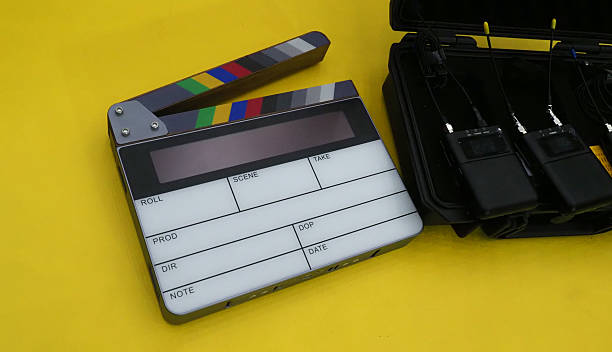 istock a digital clapperboard and a set of wireless microphone transmitters all placed on a yellow background. 2210022516