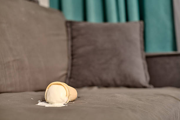 istock Fallen ice cream cone on gray sofa in living room setting 2210023850