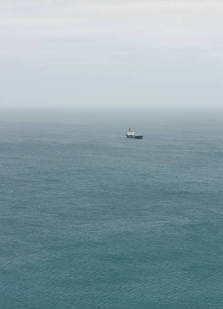 A single cargo vessel in the vast open ocean on an overcast day