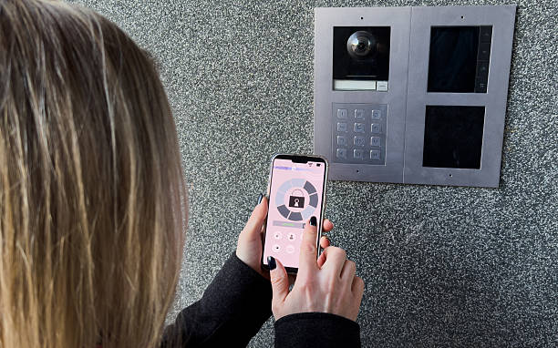 istock Woman locking smartlock on the entrance door using a smart phone. Concept of using smart electronic locks with keyless access. 2210026329