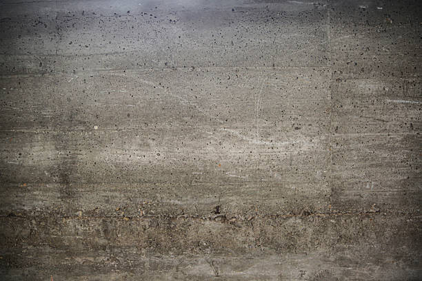Detailed view of a rough-textured concrete wall, showcasing natural gray tones and weathered surface characteristics. Ideal for backgrounds, architectural concepts, or material-themed design projects.