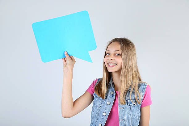 istock Young girl holding speech bubble on grey background 2210030419