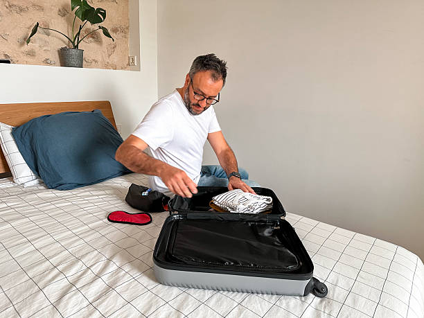 istock Packing at home: man packing a suitcase in the bedroom 2210030911