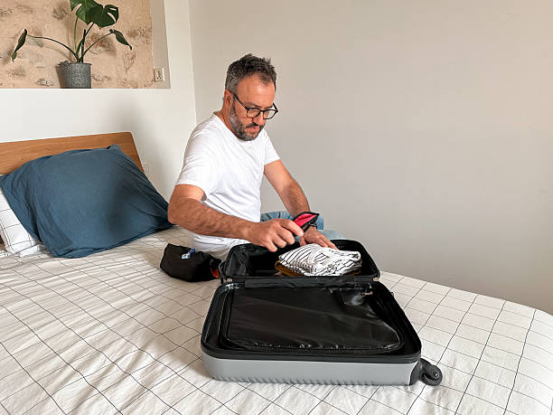 istock Packing at home: man packing a suitcase in the bedroom 2210030927