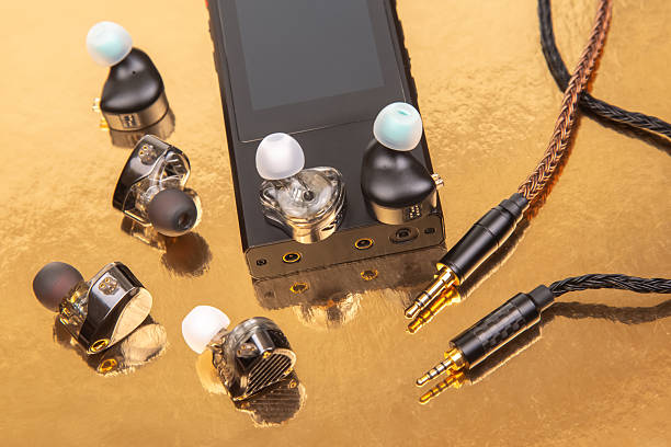 istock Three earbuds with woven cables and gold-plated jacks on a reflective golden surface, ideal for tech product shots and audio accessory themes. 2210031230