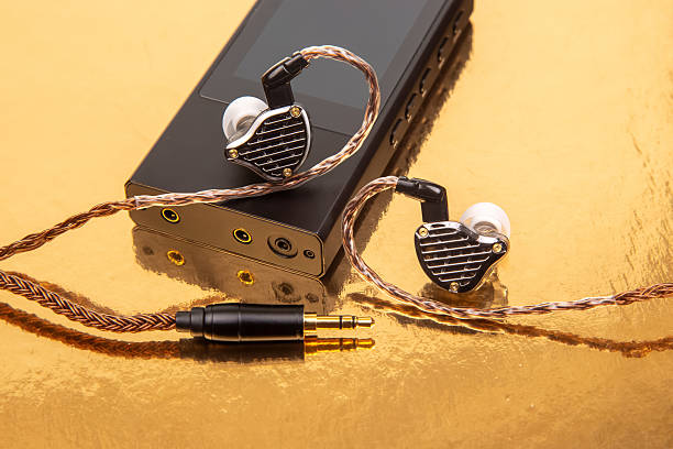 istock Elegant wired earbuds with a braided cable, placed on a black audio device against a shiny golden surface. Suitable for music, tech, and lifestyle photography 2210031659