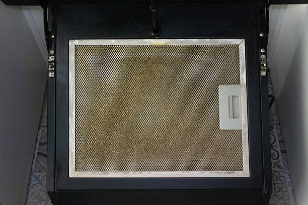 istock Dirty kitchen extractor fan filter, clogged with visible layers of cooking grease and dust, need of cleaning or replacement. 2210036345