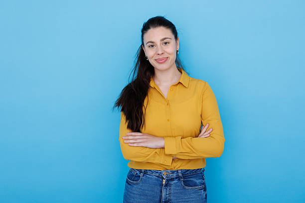 istock Confident young woman smiling, crossing arms against vivid blue backdrop 2210036620