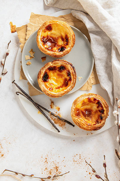 istock Three Pastel de Natas on a plate with vanilla beans and willow branches. Top view 2210037199