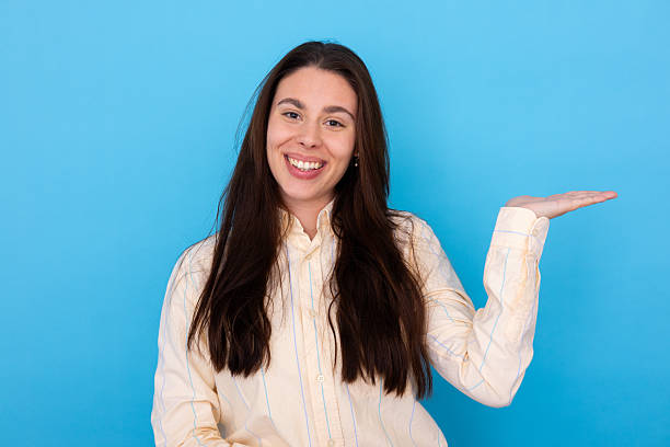 istock Young woman showing and presenting with open hand palm on blue background 2210038760