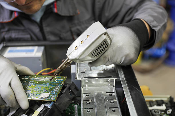 Senior computer technician (50+) performing computer maintenance. Concept: disassembly, cleaning, repair, and restoring the computer to full working condition