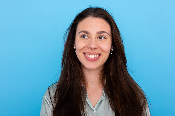 istock Cheerful woman turning head, bright smile radiating against blue backdrop 2210040204