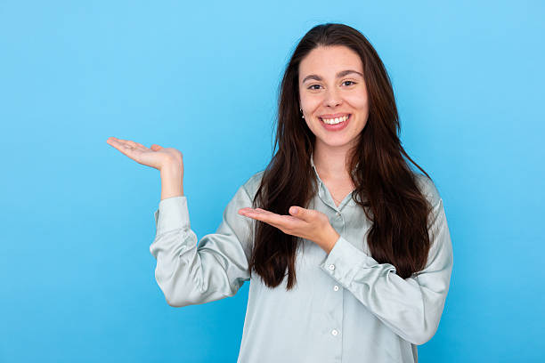 istock Young businesswoman showing and comparing with her hands on blue background 2210041023