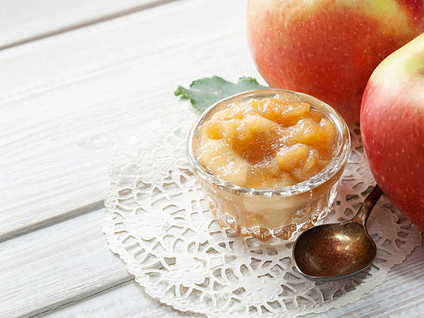 istock Small dish with apple jam with whole apples and a spoon on a white wooden table 2210045541