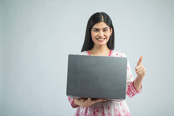 istock Woman with laptop gesturing thumbs up on white background 2210046611