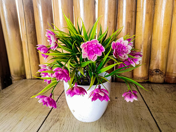 istock artificial purple blossoms tree in a white pot on wooden table with bamboo background. Copy space for text on the right side, nature or beauty banner background. 2210049332