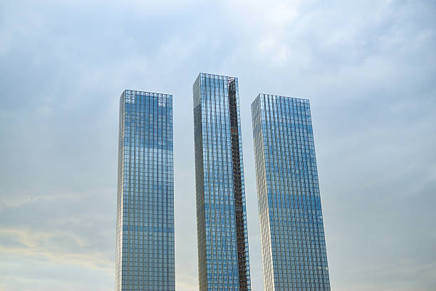 istock Three tall buildings with glass windows and a cloudy sky in the background 2210050361