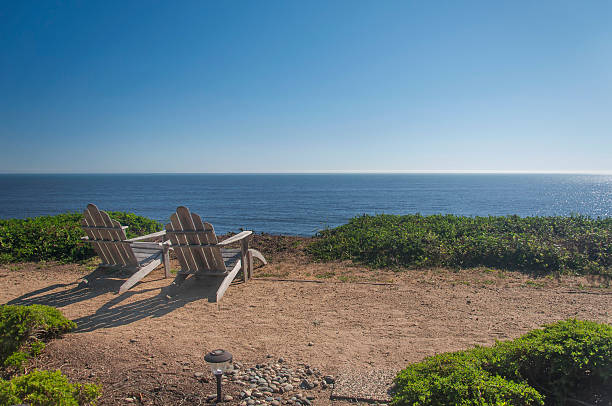 Two adirondack chairs on the edge of cliff overlooking the pacific ocean in the bay area of california on a sunny day.