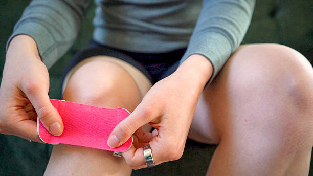 istock Putting on a pink kinesio tape 2210052053