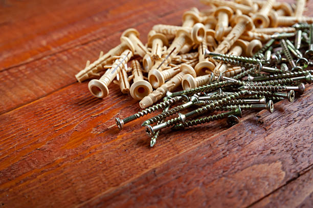 Dowels and screws closeup on a wooden background. Selective focus