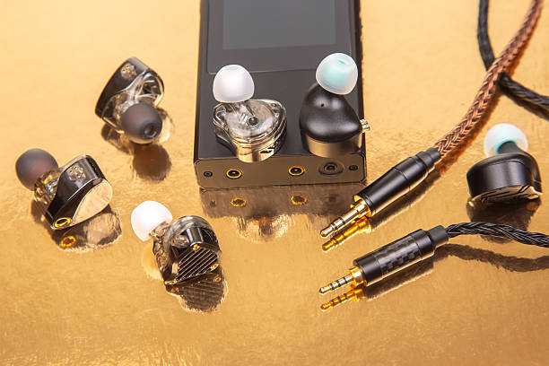 istock Three earbuds with woven cables and gold-plated jacks on a reflective golden surface, ideal for tech product shots and audio accessory themes. 2210056459