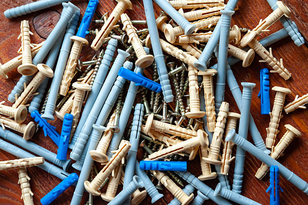Screws and plastic dowels on a wooden background. Selective focus