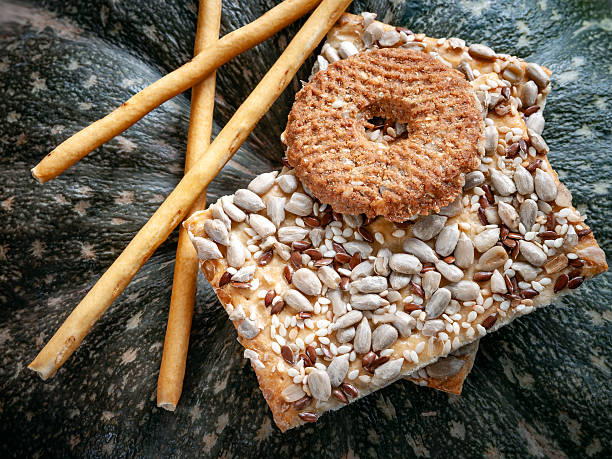 istock Crispy biscuit crackers with flax sunflower seeds and sesame against a dark pumpkin background. Daylight, selective focus 2210064887