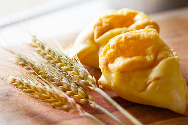 Abruzzo, Italy: fiadoni, a typical Easter speciality, with ears of wheat on a wooden table. Fiadoni are traditional savory pastries from the Abruzzo region of Italy. They’re like little cheese pies, traditionally made for Easter. The ingredients are flour, eggs, oil for the pastry, with a filling made with eggs, sharp Pecorino or other aged local cheese and sometimes  ricotta for a softer texture. In Abruzzo, fiadoni are a big part of Easter food traditions and often made in big batches to share.