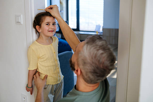 istock Father measuring his daughter's height at home. 2210074297