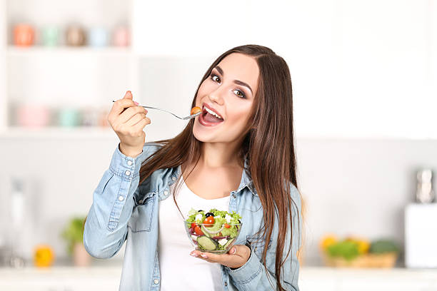 istock Beautiful woman eating fresh salad in the kitchen 2210078657