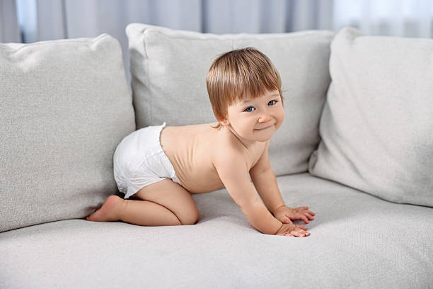 Little child in diaper on sofa at home