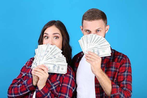 istock Young couple with dollar banknotes on blue background 2210081495