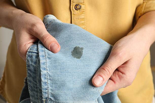 istock Washing clothes. Woman holding jeans with stain, closeup 2210081663