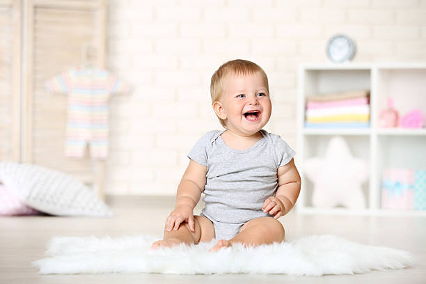 istock Happy baby boy sitting on carpet at home 2210082851