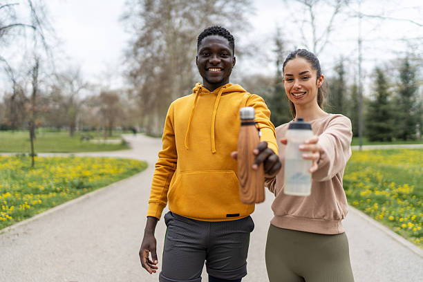 istock Smiling couple standing together with water bottles in park 2210083793