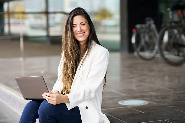 istock A Smiling Young Woman Happily Working on Her Laptop While Outdoors in a Bright Environment 2210083918