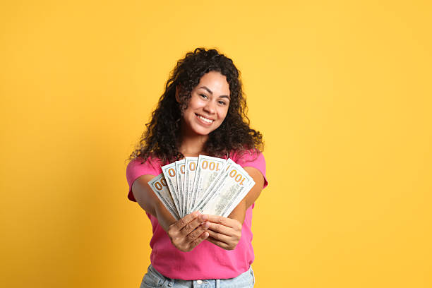 istock Happy woman with dollar banknotes on yellow background 2210084234