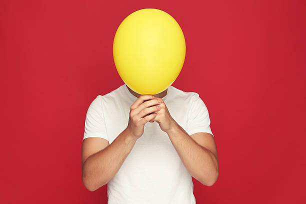istock Yuong man with balloon on red background 2210084651