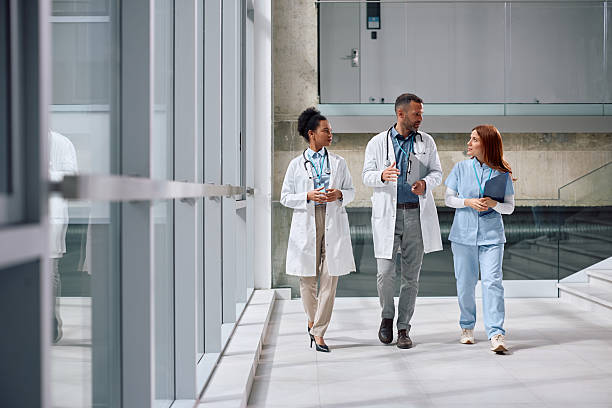 istock Group of doctors communicating while walking through hallway at the clinic. 2210086619