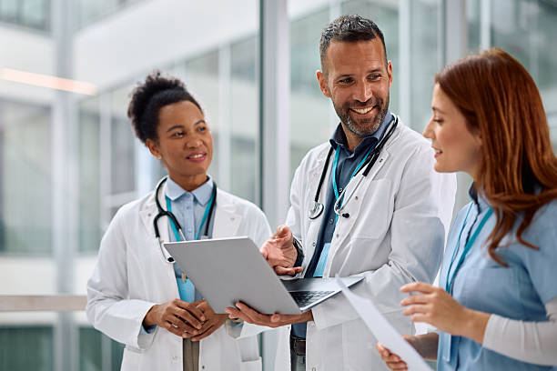 istock Happy doctor using laptop with female colleagues while working at the clinic. 2210086672