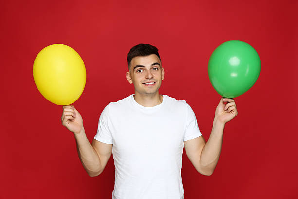 istock Yuong man with balloons on red background 2210086678