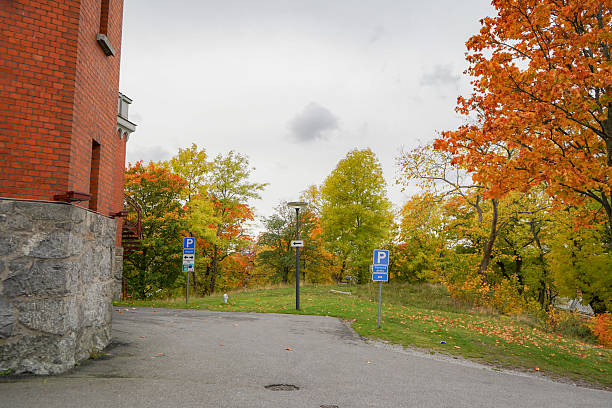 Corner of an old brick building with colorful autumn leaf trees in orange and yellow colors, Sweden